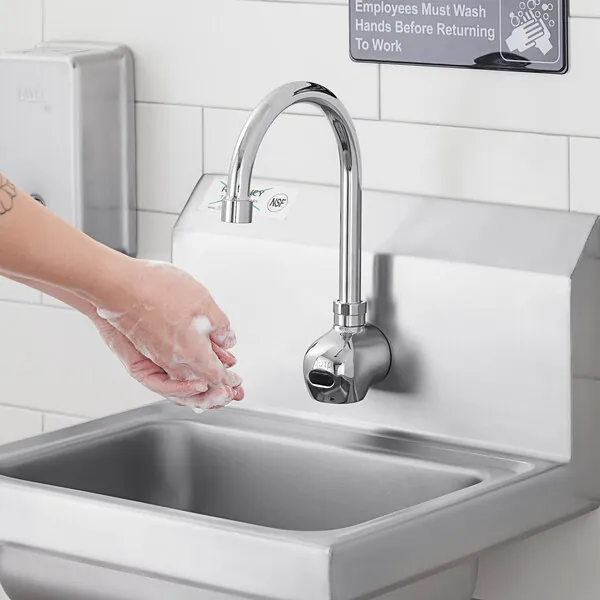 Cleaning the infrared sensor window on a modern faucet with a soft cloth.