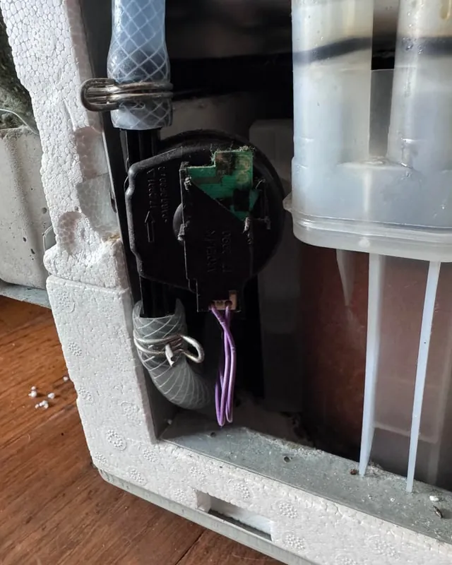 A dirty dishwasher filter is being removed for maintenance and cleaning.