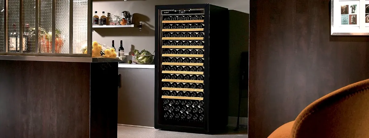 A hand inspects the magnetic door seal of a wine cabinet for air leaks.