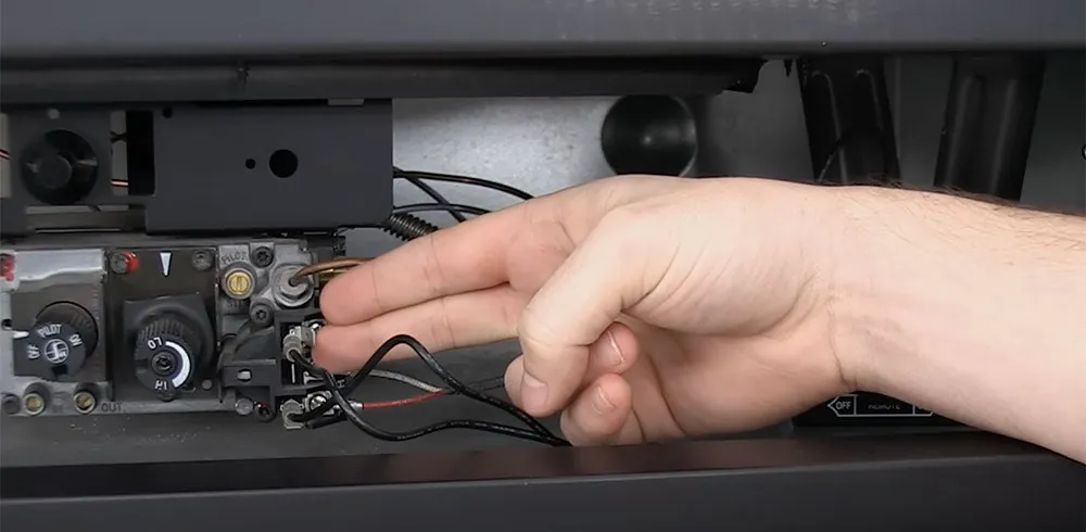 A person carefully installing new batteries into a fireplace remote control unit.
