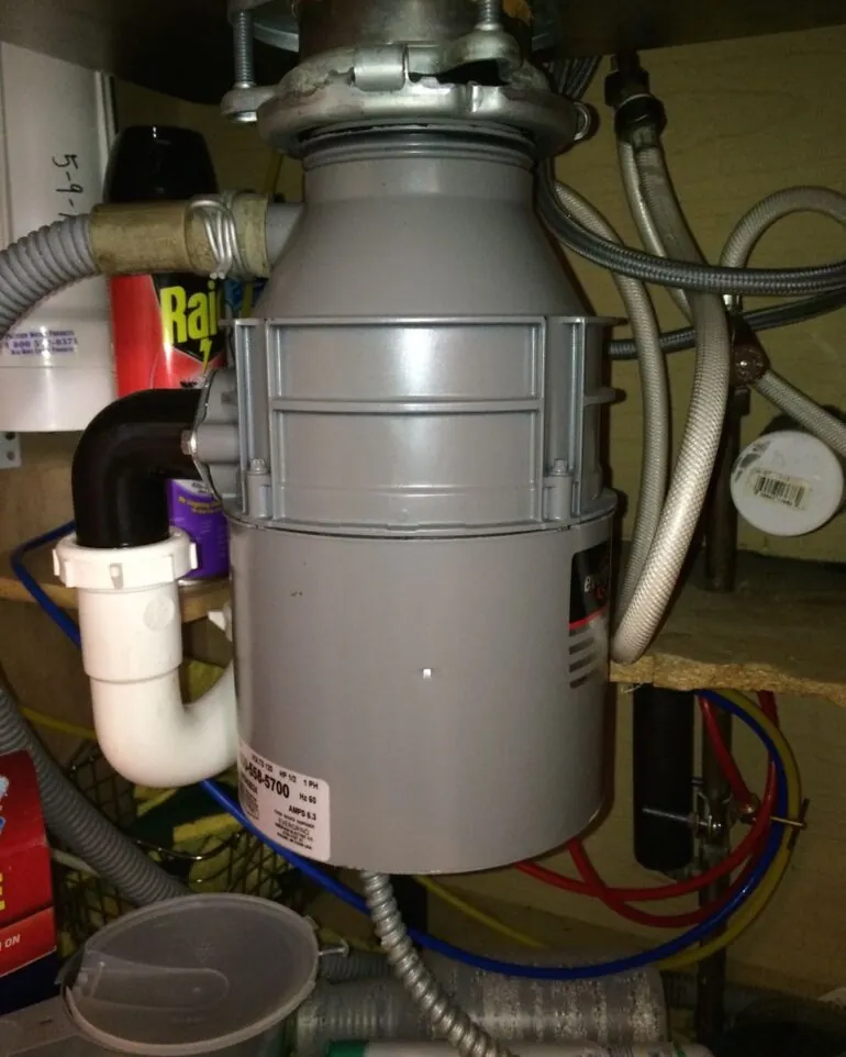 Pouring cold water into a kitchen sink to maintain the disposal unit.