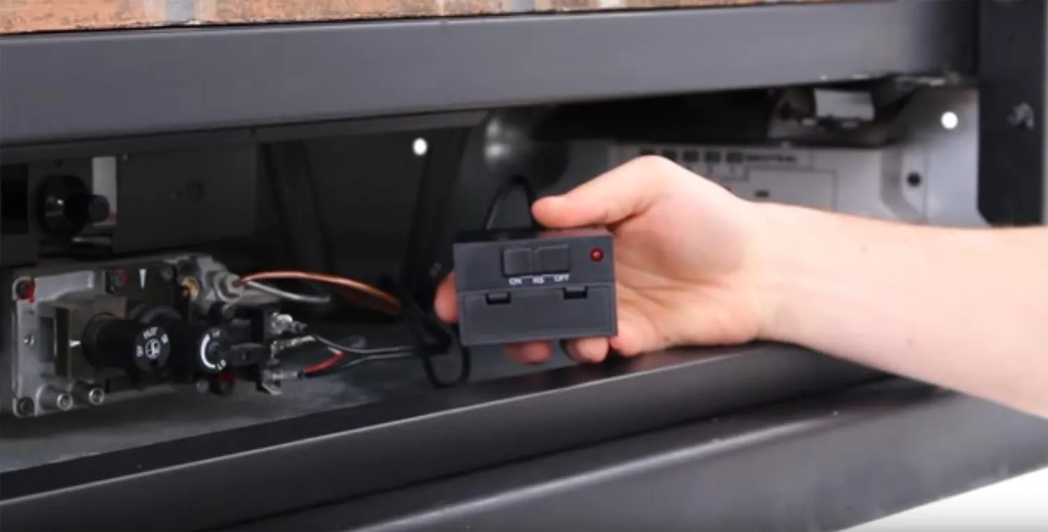 A steady pilot light flame burning inside a modern gas fireplace unit.