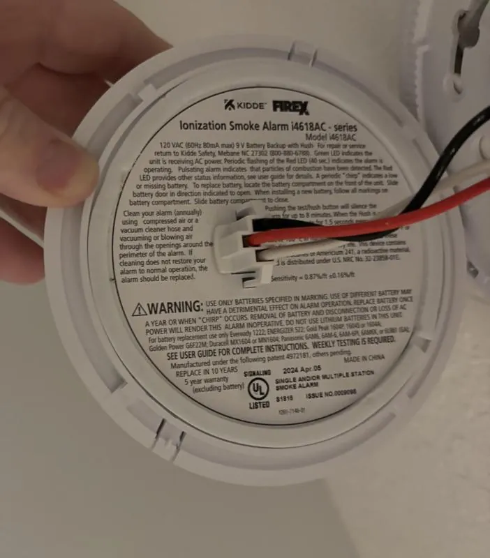Dust and spider webs inside an open smoke alarm sensing chamber causing issues.