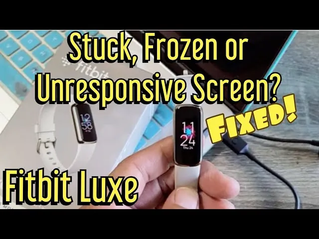 A Fitbit Luxe device attached to a charging cable during a troubleshooting session.