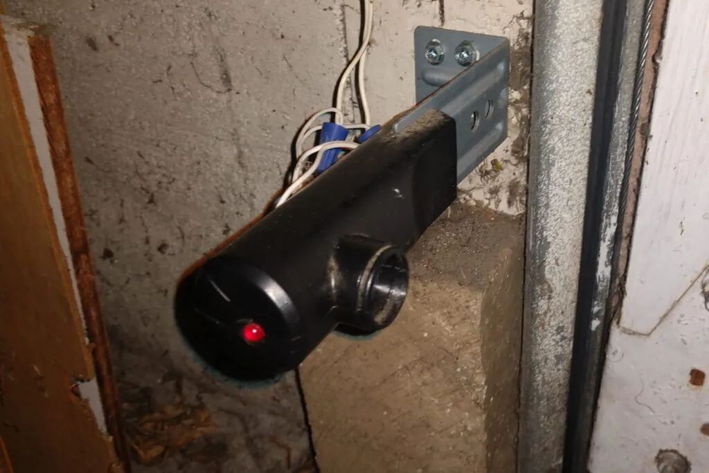 Hands carefully securing wiring connections into a garage door opener terminal port.