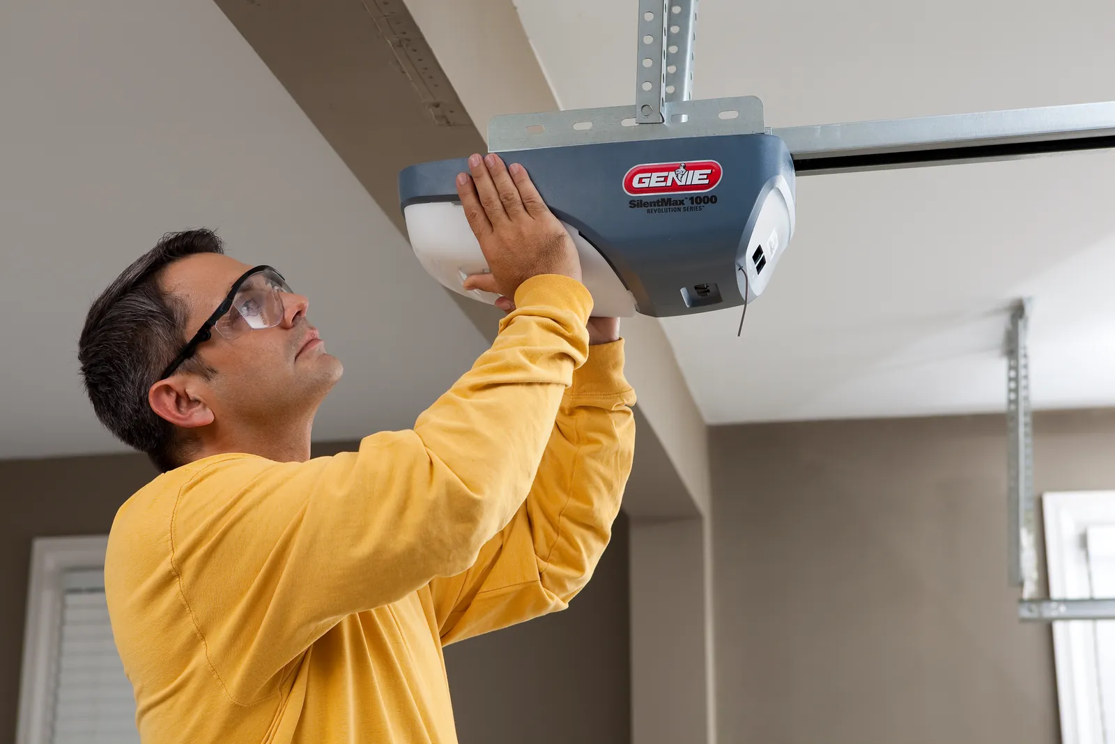 Person cleaning garage door tracks with a dry cloth to prevent operational issues.