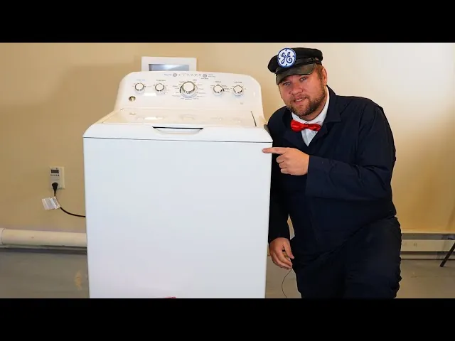A technician inspects the internal electronic circuit board of a washing machine.