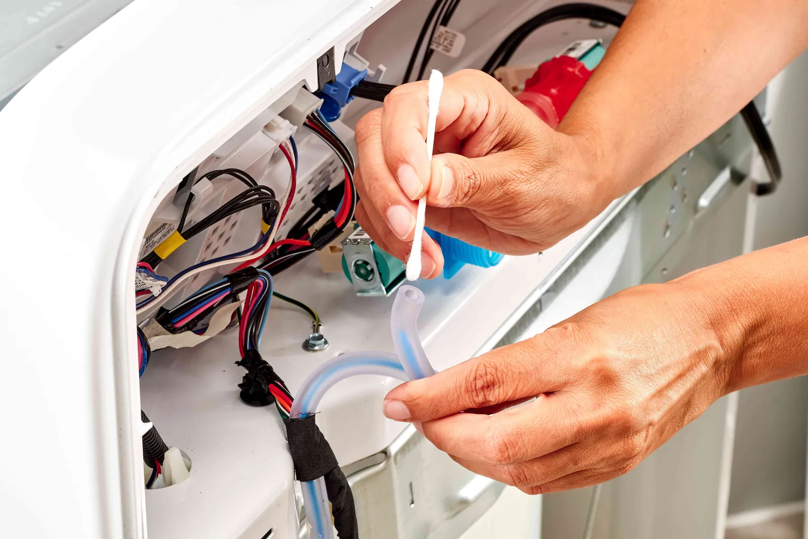 A washing machine pressure switch and air tube sit on a workbench for troubleshooting.